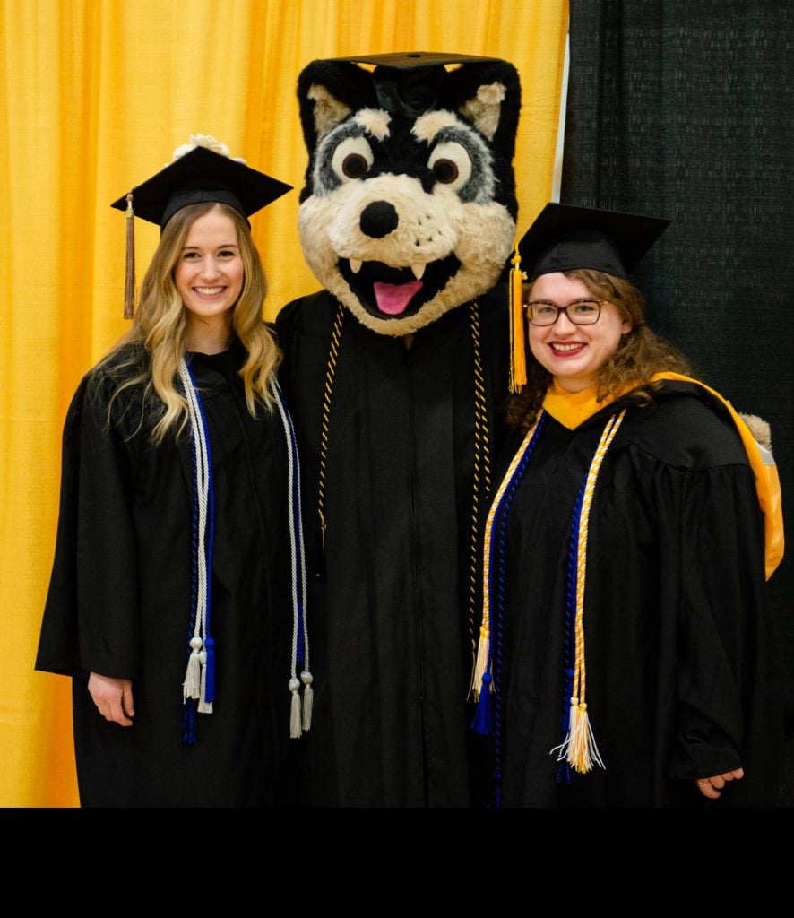 Two students flank mascot Blizzard during Commencement