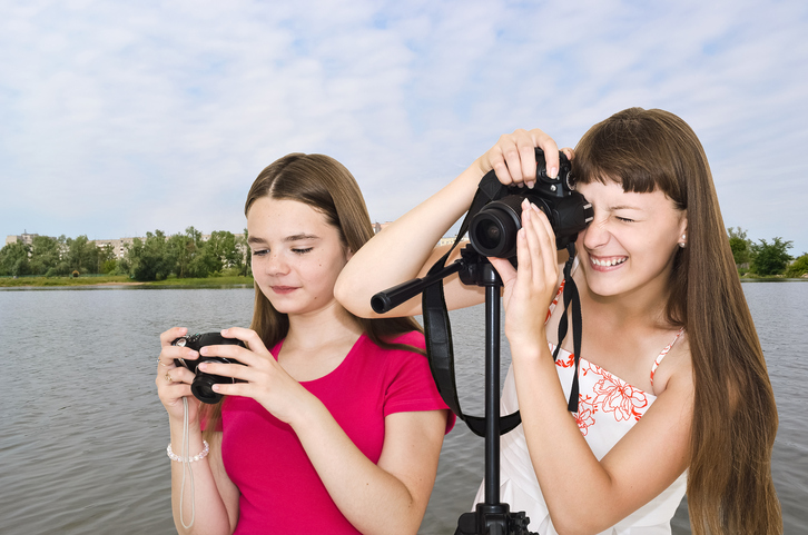 Two photographer teen girls outdoors by the river