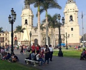 People standing in front of a large temple on a city street in Lima, Peru