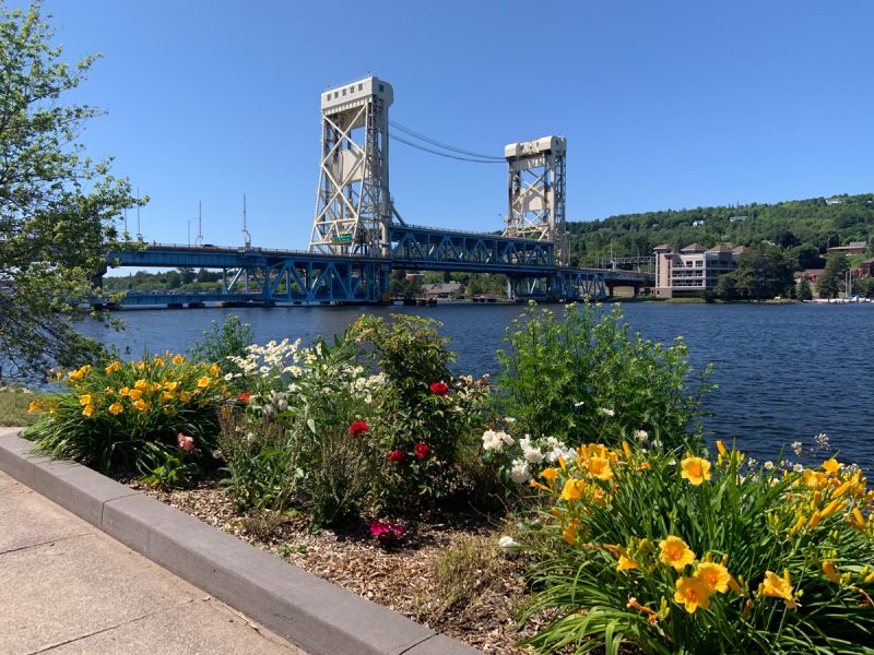 Portage Lake Lift Bridge with flowers blooming in the foreground.