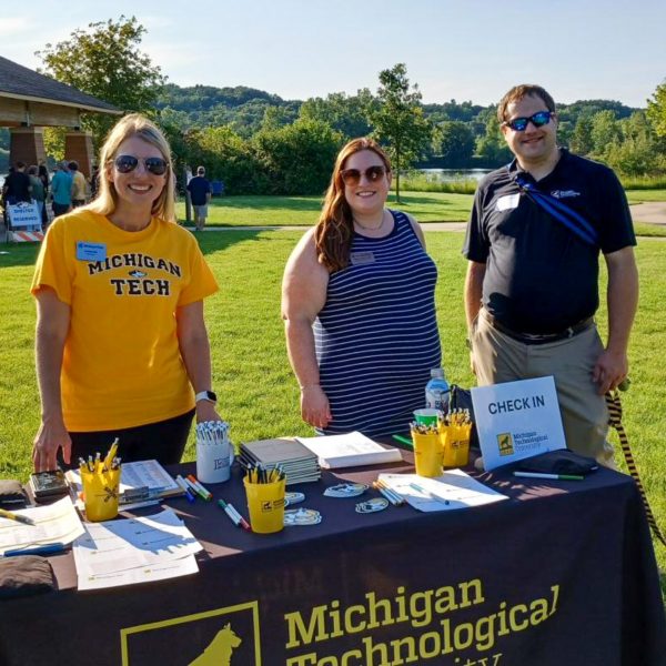 Regional Admissions Manager Jennifer Todd, and alumni hosts Emma '12 '16 and Adam '16 Zawisza assist with check-in and door prizes