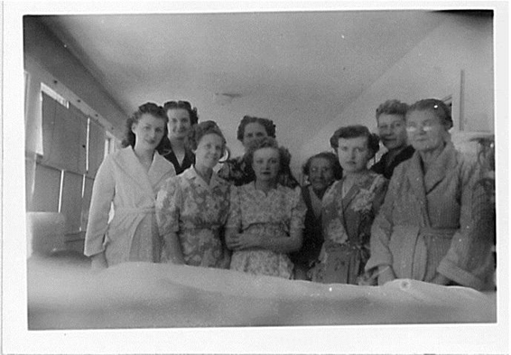 A group of women being treated for tuberculosis at the Copper Country Sanatorium in 1950 pose for the camera in bathrobes and house dresses.