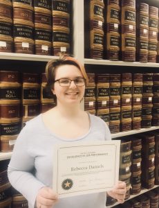 Becky poses with her certificate by the State Records Collection in the Archives stacks.