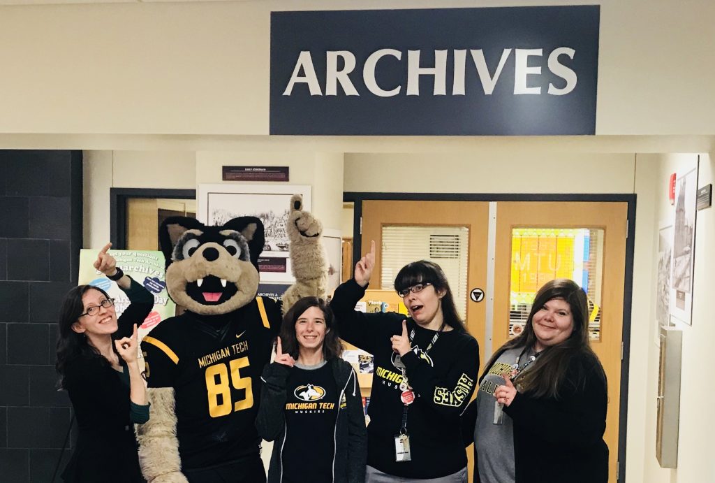 The current archives team poses with Blizzard T. Husky on #AskAnArchivist Day, 2018. From left, Allyse, Blizzard, Allison, Emily, and Lindsay.