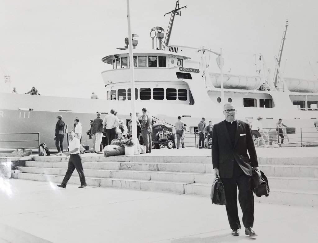 Priest in front of large boat