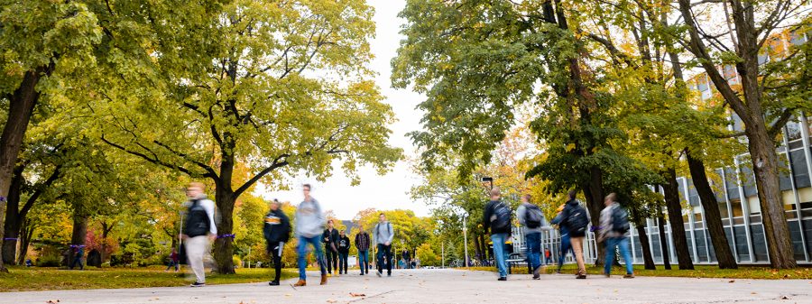 Blurred students walking across Michigan Tech's campus in summer.