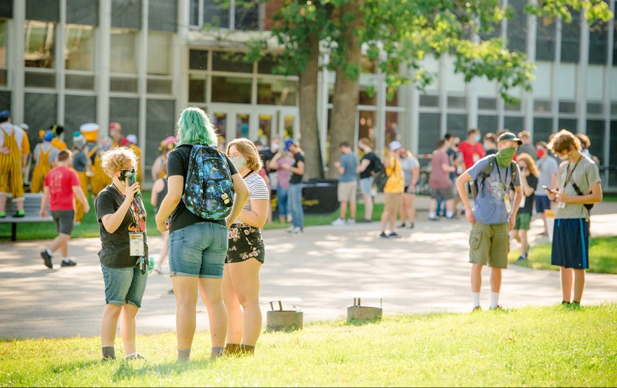 Several small groups of students gather together outside on Michigan Tech's campus on a sunny day.