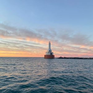 Lighthouse on the water with a sunset background