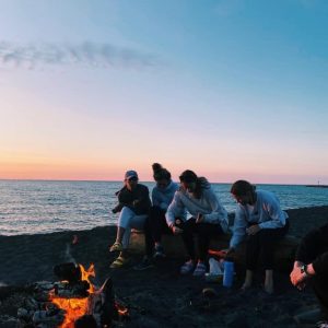 Kate and friends sitting by a campfire during sunset