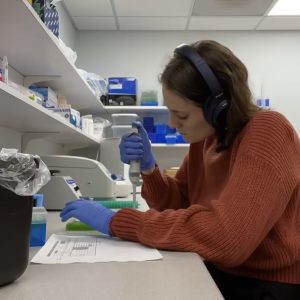 A picture of Tessa in the lab using a pipette to transfer a sample. 