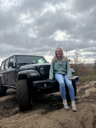 Woman sitting on a Jeep with cloudy skies