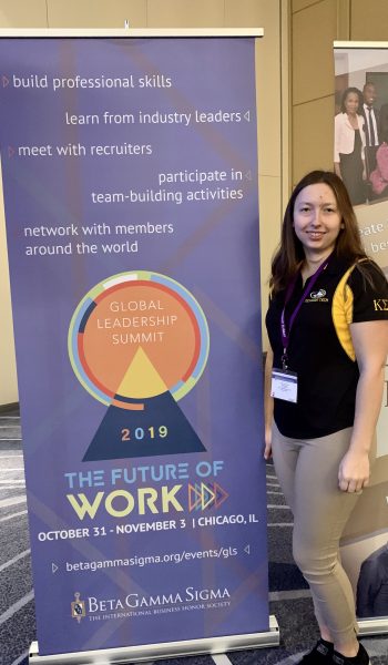 Student stands in front of pull-up banner at conference