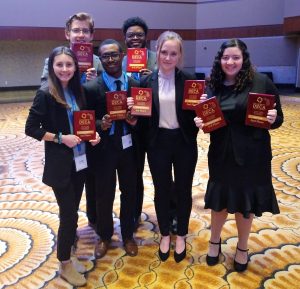 Students standing in a group with DECA plaques