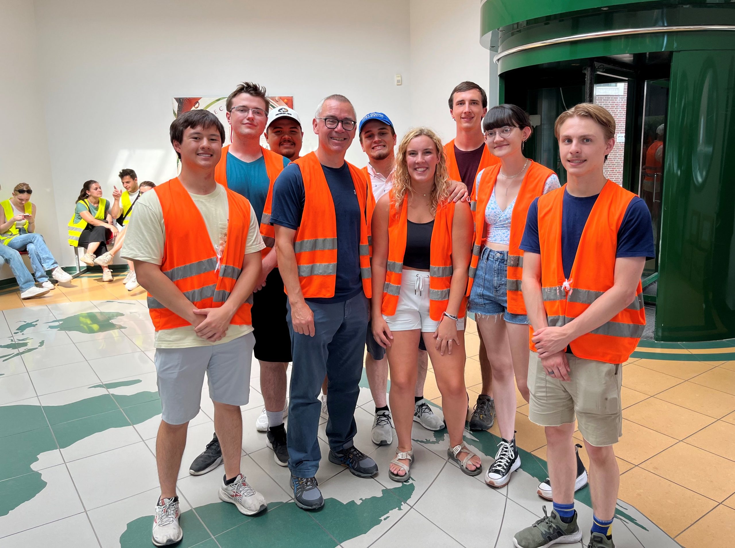 Group of students in orange vests pose during a plant tour