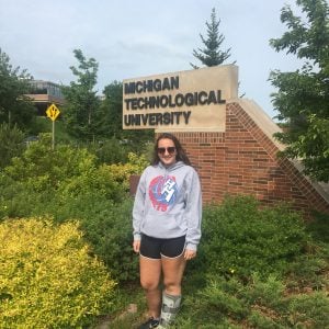 Emily Kughn stands in front of a Michigan Tech sign