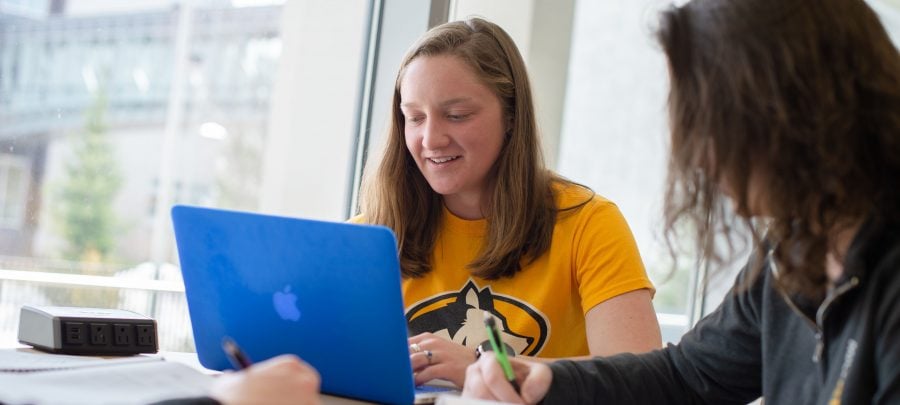 Two graduate students in the Michigan Tech College of Business discuss advanced degree programs while looking at a laptop computer.