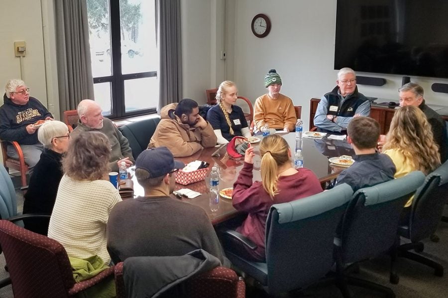 A group of people gather in a conference room in the Michigan Tech College of Business to talk about careers and college studies while enjoying pizza.