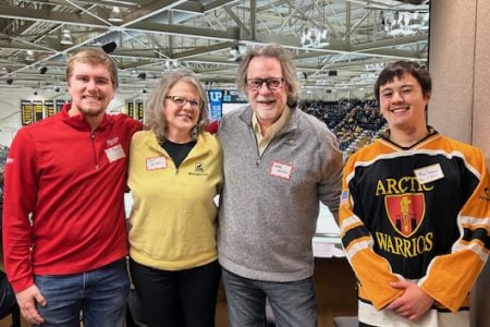 Alum Greg Horvath and wife Beth spend time with their MIS scholarship recipients, Max Schramm, left, and Ty Sheets, in the Winter Carnival Hockey Box. (Image credit: Marie Cleveland)