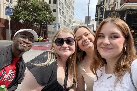 Four smiling students in downtown San Francisco exploring the city as part of attending an international competition.