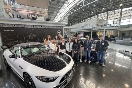 Michigan Tech students pose in front of a Mercedes-Benz car while visiting with the company.