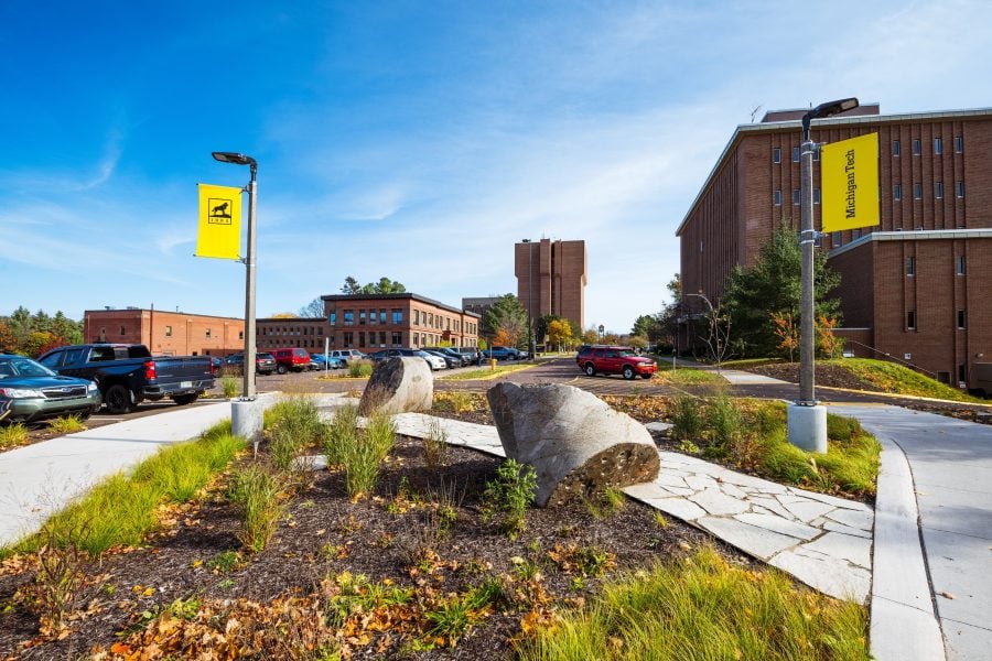 Michigan Tech campus in the fall, facing eastward with colorful trees and leaves with buildings in the distance.