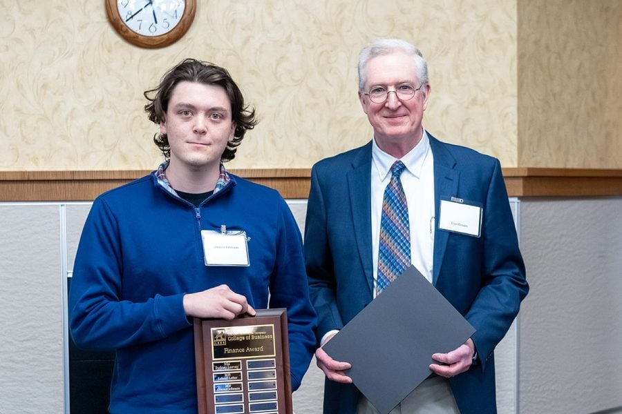 Michigan Tech student Connor Johnson receives an award plaque from Dan Green. Both are in business attire.
