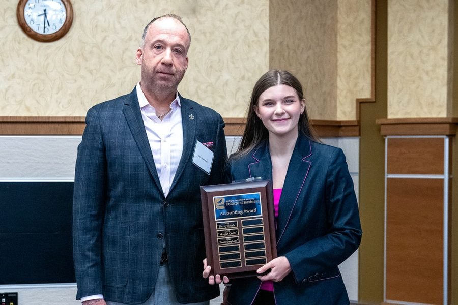 Michigan Tech student Coralee Daugherty receives an award plaque from Paul Hammes. Both are wearing business attire.