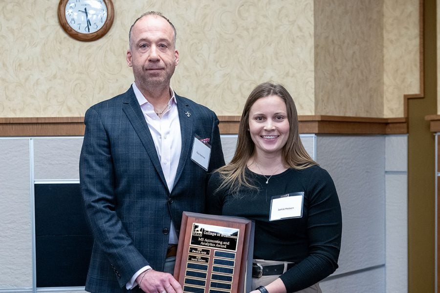 Michigan Tech student Jamie Meleen receives a plaque from alumnus Paul Hammes. They are both wearing business attire.