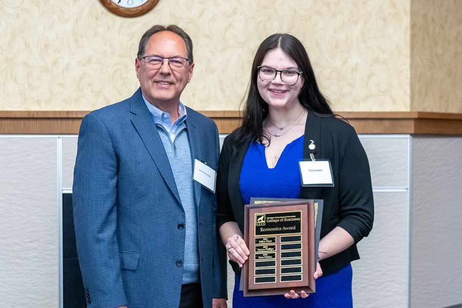 Michigan Tech student Tessa Bakker receives an award plaque from alumnus Kevin Wampler. They are both in business attire.