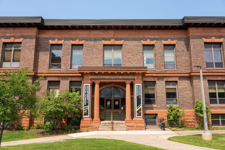 The exterior of the College of Business at Michigan Tech in summer, fronted by a green lawn.