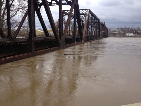 Steel railroad bridge spanning a flooded river.