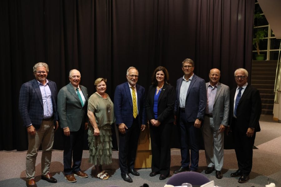 CEGE Academy inductees stand together on stage at Michigan Tech’s Rozsa Center, dressed in formal and business attire, smiling for a group photo following the 2025 Academy Induction Ceremony.
