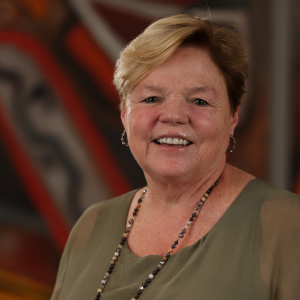 Karol L. Grove, wearing a sage green blouse and a beaded necklace with a silver floral pendant, smiles for a professional portrait taken during the 2025 CEGE Academy Induction Ceremony at Michigan Tech.