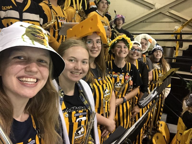 Huskies Pep band members holding flutes and wearing funny hats
