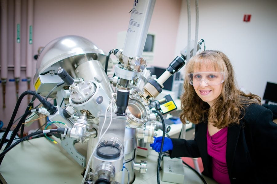 Katherine Perrine next to a scanning electron microscope.