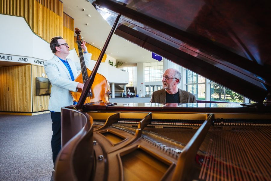 A professor on stand-up bass and another seated at the grand piano play together in the lobby of Michigan Tech’s Rozsa Center for the Performing Arts.