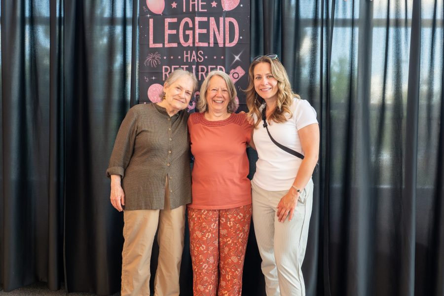 Linda Ott and two other people standing in front of a sign reading "The Legend has Retired".