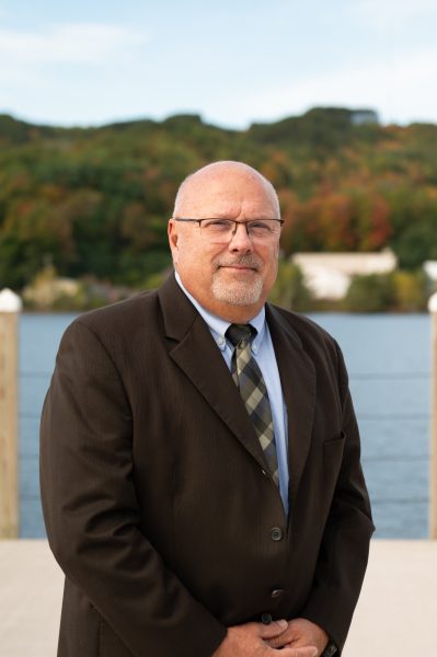 Formal portrait of Michigan Tech College of Computing Inductee Mark Gauthier on the Portage Canal with fall foliage in the background.