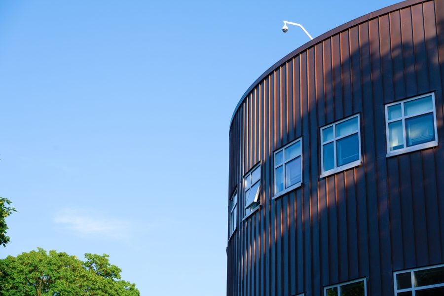 Exterior view of Rekhi Hall with trees in view and a blue, clear sky.