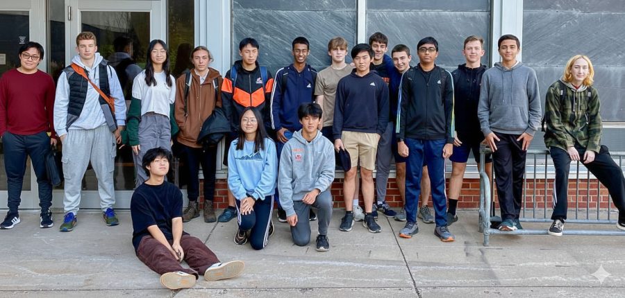 17 high school students pose in a line in a doorway near a bike rack while on the Michigan Tech campus learning cybersecurity.