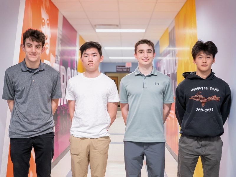 Four high school students on the CyberHusky team led by the Michigan Tech College of Computing stand in the hallway of the college.