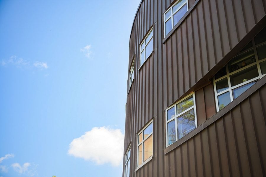 The exterior of the Michigan Tech College of Computing’s Rekhi Hall headquarters on campus with a blue summer sky and white clouds in the background.