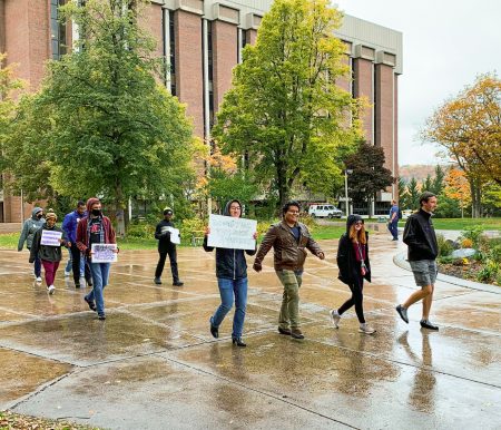 People walk across Michigan Tech's campus, some holding signs in support of domestic violence survivors.