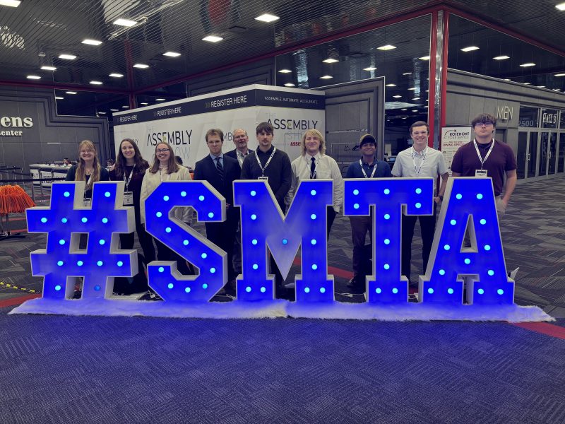 Students standing in front of blue letters that spell out "#SMTA"