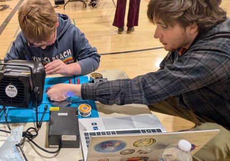 Alex Ossenheimer helping a student build a mini flashlight
