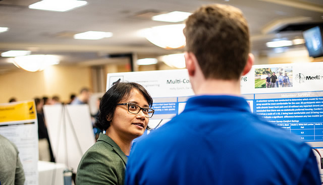 Design Expo 2018 showing a person talking to a student at their poster