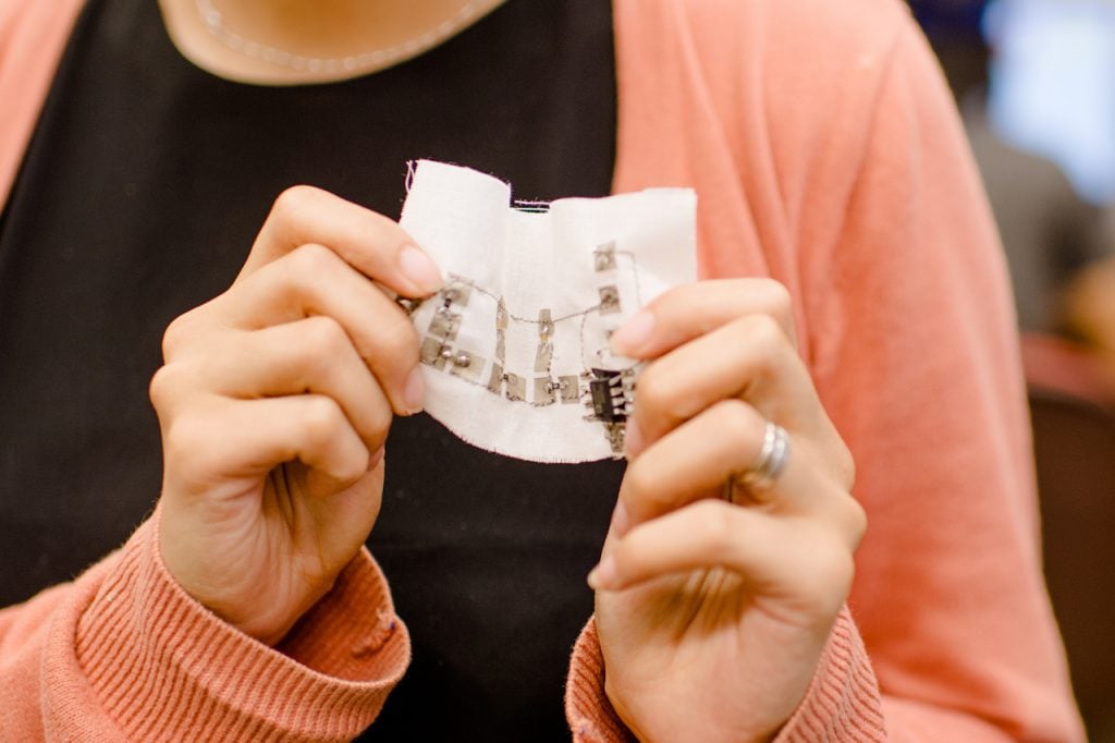 Ye Sarah Suns hands are show holding a prototype of a flexible electronic circuit, where the stitches themselves become the circuit.