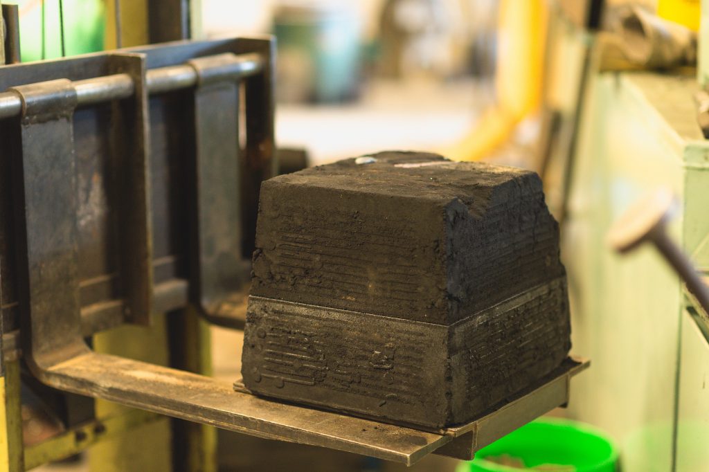 A mold with a casting inside is transported to the shake-out bin.