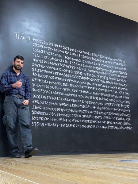 Estafanio Kesto standing near a chalkboard with many digits of Pi.