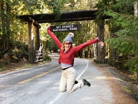 Josie does a happy jump in front of the Mount Rainier lodge sign